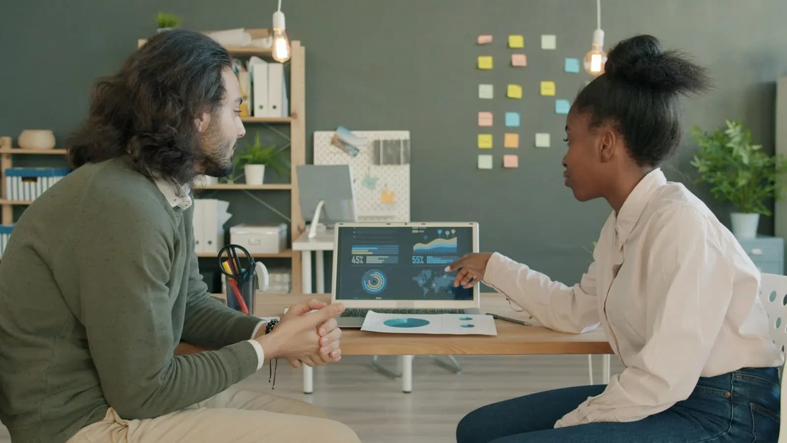 Two colleagues discussing figures on a laptop